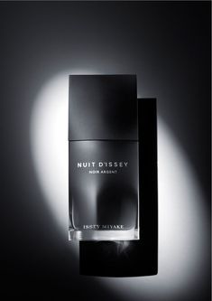 a bottle of perfume sitting on top of a black table next to a box with the word nuit dissey written on it