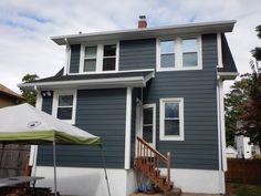 a blue house with a white umbrella in front of it and some stairs leading up to the second floor