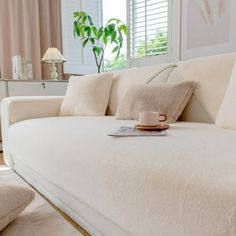 a white couch with pillows and a cup on it