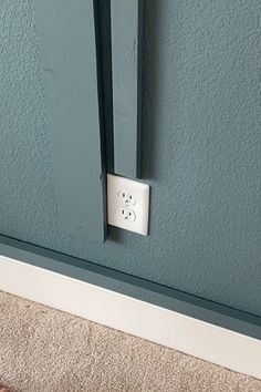 a white light switch sitting on the side of a wall next to a carpeted floor