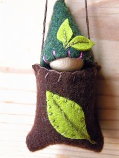 a felt ornament hanging on a wooden wall with leaves and acorns