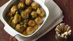 a white bowl filled with meatballs on top of a table next to a napkin