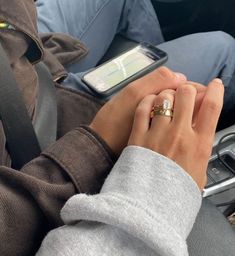 a woman is holding her cell phone while sitting in the back seat of a car