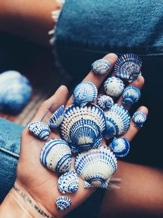 a woman's hand holding several seashells in blue and white designs on her palm