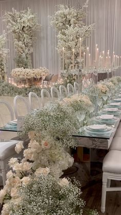 a long table is set with white flowers and candles