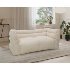 a white couch sitting on top of a rug in a living room next to a window