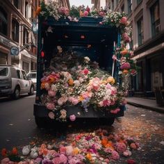 a truck with flowers on the back driving down a street