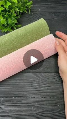 a person holding a yoga mat on top of a wooden table next to a plant