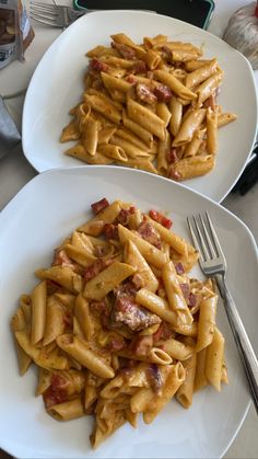 two white plates with pasta and meat on them