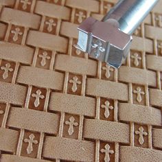 a close up of a metal object on a woven surface with crosses and cross cutouts