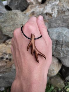 a person wearing a bracelet with an antler on it's wrist, in front of some rocks