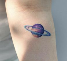 a small saturn tattoo on the arm