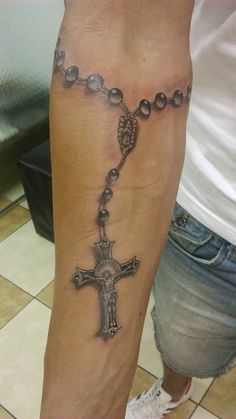 a person with a rosary tattoo on their arm