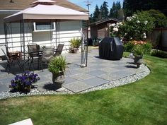 an outdoor patio with chairs and umbrellas in the back yard, next to a house