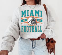 WELCOME TO MY STORE ♥️ This Miami Football Crewneck, Vintage Miami Football Sweatshirt, Dolphins Sweatshirt, Miami Fan Gift, Phins Sweatshirt, Fins Shirt, University Miami, Miami Gift, Miami Dolphin, Miami Sweater, Sunday Football, Football Lovers, Gift for her, Gift for him, Game Day Shirt, American Football , Super Bowl Shirt, Christmas Gifts, Birthday Gifts. *Please check Color and Size Charts before placing the order. You can find them in the listing's photos (Depending on what device you ar Retro Miami, Miami Shirt, Football Fan Shirts, Florida Football, Sweat Vintage, Miami Football, Miami Dolphins Football, Vintage Miami, Dolphins Football