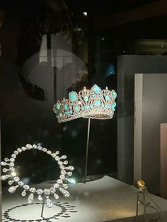 a tiara is on display in a window with other items behind it, including a necklace and ring