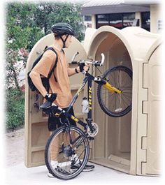 a man standing next to a bike in front of a small structure with an open door