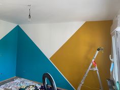 a room that has been painted with different colors and shapes on the wall, along with a ladder