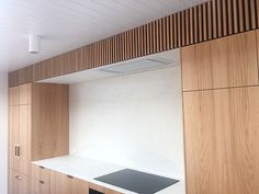 an empty kitchen with wooden cabinets and white counter tops, along with black stovetop