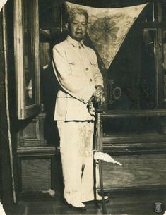 an old black and white photo of a man holding a cane in front of a painting