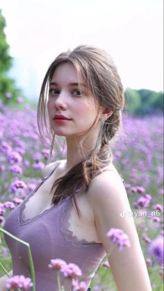 a woman standing in a field of purple flowers with her hair pulled back and eyes closed