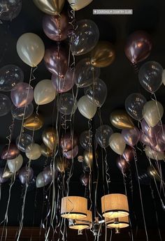 many balloons are floating in the air with lights on them and hanging from the ceiling