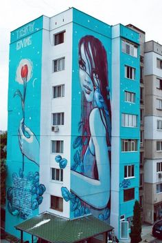 a large blue building with a mural on it's side next to a parking lot