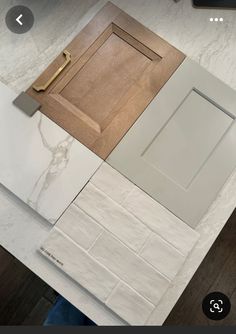 a kitchen counter top with white tile and wooden cabinet doors in the center, next to a laptop computer