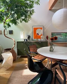 a dining room table and chairs in front of a potted tree