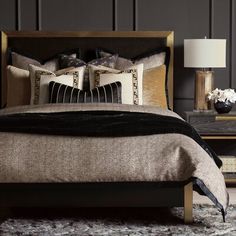 a bed with two pillows on top of it next to a night stand and lamp