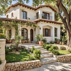 a large white house with lots of windows and plants on the front lawn in front of it