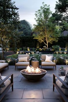 an outdoor fire pit surrounded by chairs and tables in the middle of a garden at night