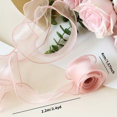 pink flowers and ribbon on top of white paper