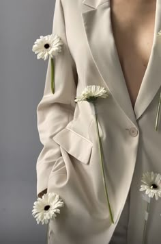 a woman in a white suit with flowers pinned to her lapel and buttons on the back