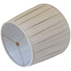 a white and brown checkered lamp shade with gold trim on the top, in front of a white background