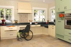 a wheelchair is in the middle of a kitchen with white cabinets and light green cupboards