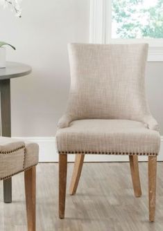 a pair of beige upholstered chairs sitting in front of a white wall and wooden floor