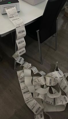 a pile of paper sitting on top of a table next to a printer and some chairs