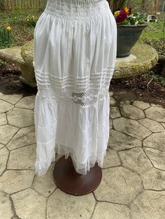 "Seashore? Sure! Picnic? Positively! This white 100% cotton skirt from ETC. in the 1980s is elasticized at the waist and has 4 rows of smocking just below the waistband.  Further down, you'll find 4 rows of pin-tucking followed by an insert of crochet lace.  At the bottom it's finished off with 2 tiers of soft net ruffles.  Lined to 24\" down.  In great condition.    Waist 28\" stretches to 50\" Hips 54\" Length 32\"" White Skirt For Summer Garden Party, White Skirt With Smocked Bodice For Spring, Vintage Ruffled Petticoat For Spring, Vintage Spring Petticoat With Ruffled Skirt, Vintage Ruffled Spring Petticoat, Cottagecore Tiered Summer Skirt, Summer Cottagecore Tiered Skirt, Cottagecore Tiered Skirt For Summer, White Fitted Bottoms With Smocked Bodice