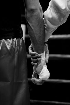 two people holding hands while standing next to each other in front of a boxing ring