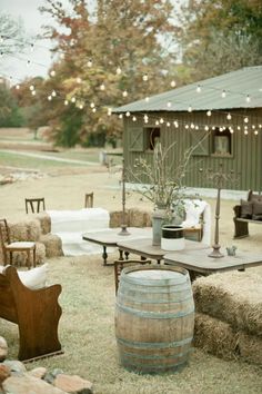 an outdoor setting with hay bales and lights strung from the roof, chairs, tables, and couches