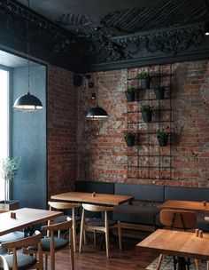 an empty restaurant with brick walls and wooden tables in the foreground, hanging planters on the wall