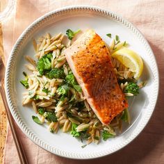 a white plate topped with fish and broccoli on top of a wooden table