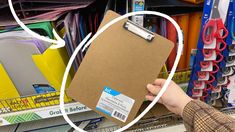 a person holding a clipboard in front of a store shelf filled with craft supplies