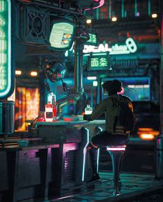 a man sitting at a table in the middle of a street with neon lights on it