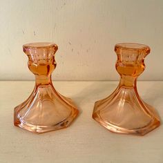 two orange glass candlesticks sitting on top of a white countertop next to each other