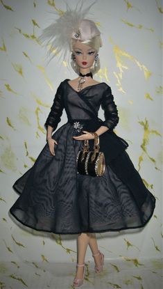 a barbie doll wearing a black dress and hat with feathers on it's head