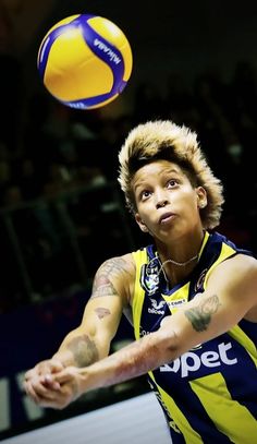 a man in a yellow and blue uniform hitting a volleyball