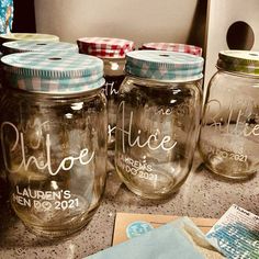 four mason jars with labels on them are sitting on the counter next to some papers