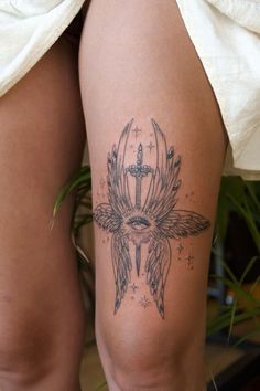 a woman's thigh with a cross and wings tattoo on it